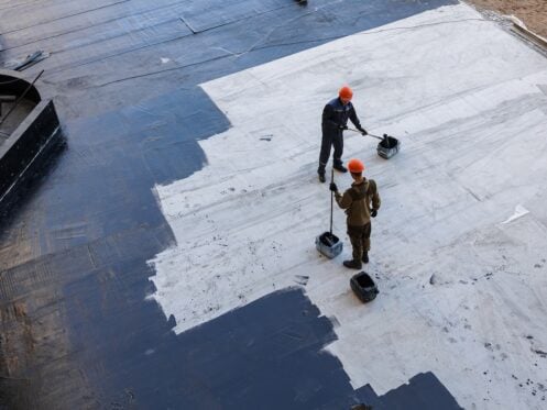 Waterproofing coating. A worker applies bitumen mastic to the foundation. Roofer cover the waterproofing primer on the roof, modified with polymer bitumen, with a roller brush.