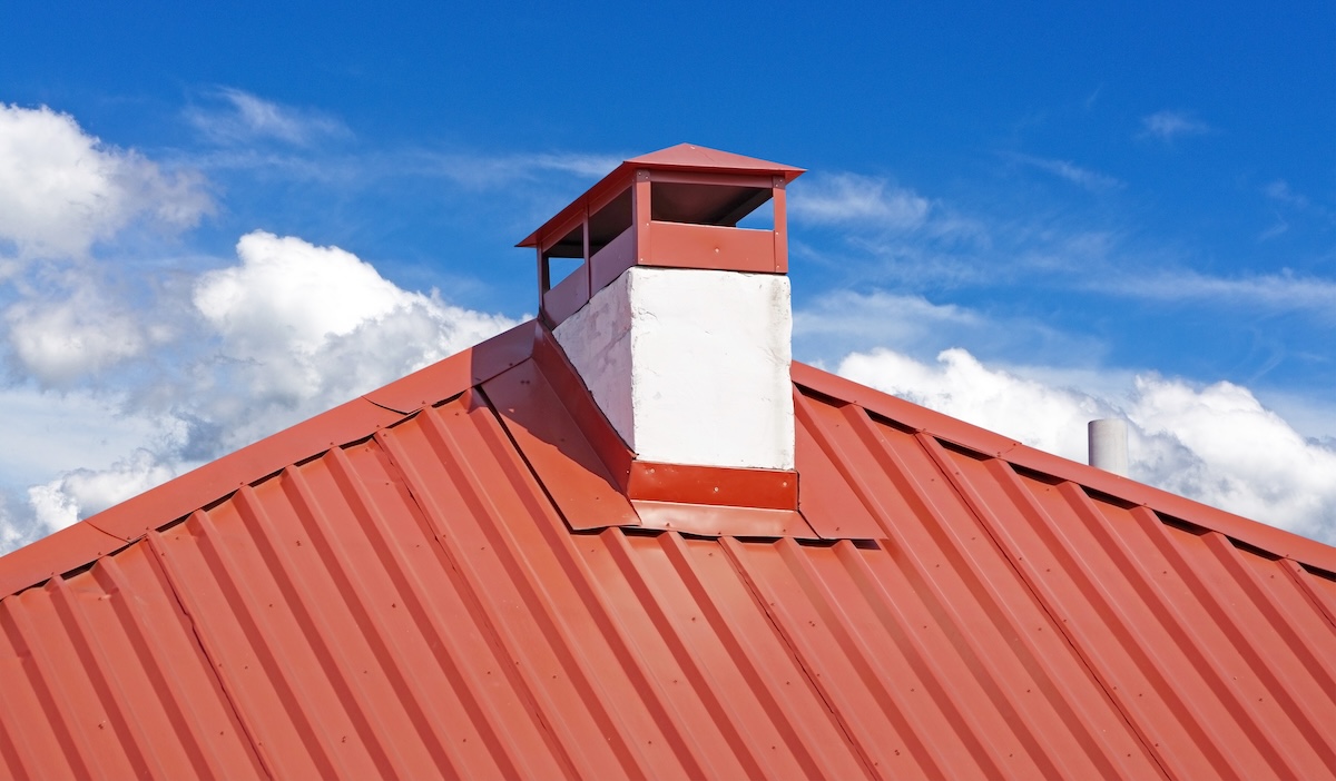 chimney on the roof of the house against the blue sky with metal base