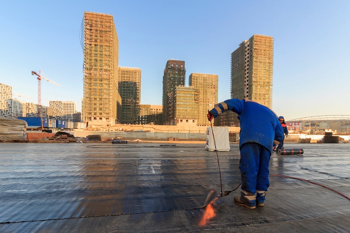 Waterproofing the roof of residential building. Covering roofing material. flat roof with roofing and fencing.