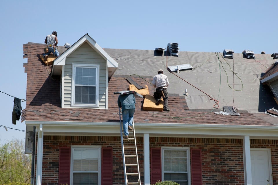 does a new roof increase home value-roofing crew replacing shingle roof on a brick house