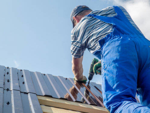 metal roof installation-roofer installing panels of metal roofing on a house